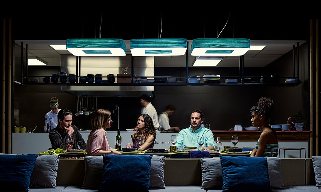People dining at a restaurant table illuminated by LZF's Cuad wooden lamps