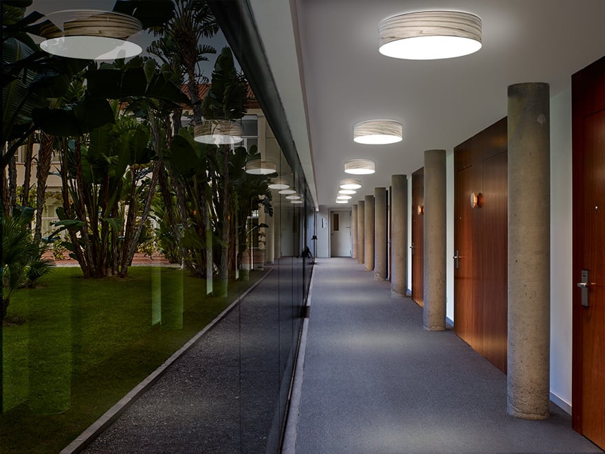 Pasillo de hotel iluminado con lamparas de aplique circulares de madera de LZF