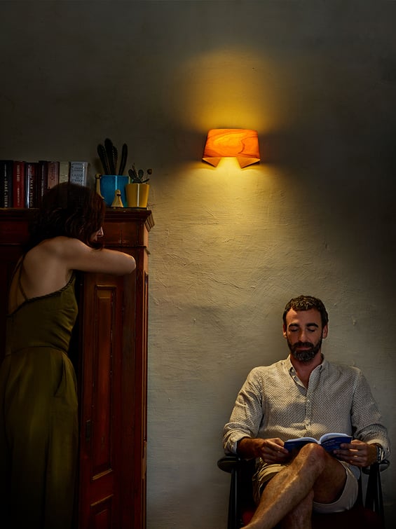 Man reading by the light of a yellow wooden wall lamp by LZF