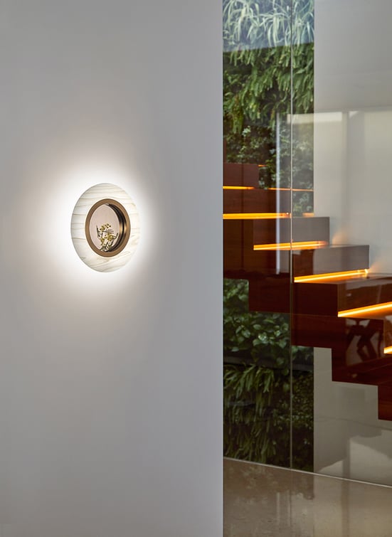 Circular wall light of wood veneer with central mirror next to the stairs of a house