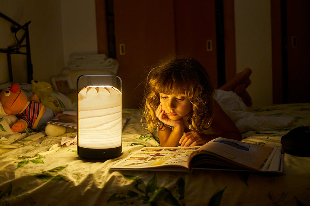 Girl reading with portable wooden and metal lamp