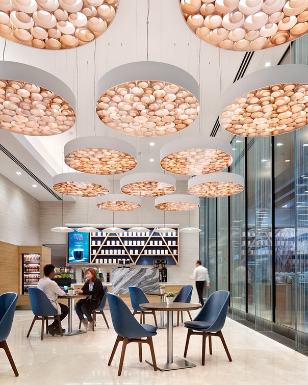 Hospital cafeteria with circular suspension lamps whose frame contains a mass of irregular spirals of wood veneer