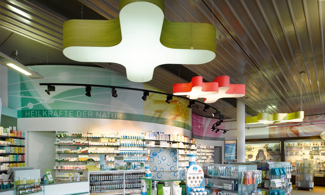 Lamps made of wood veneer and in the shape of an X illuminate a pharmacy