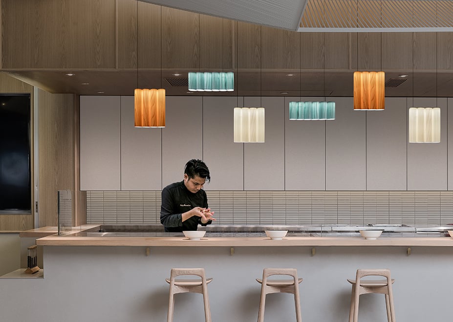 Japanese restaurant-bar-illuminated-with-wood-veneer-lamps-whose-design-evokes-the-spines-of-books